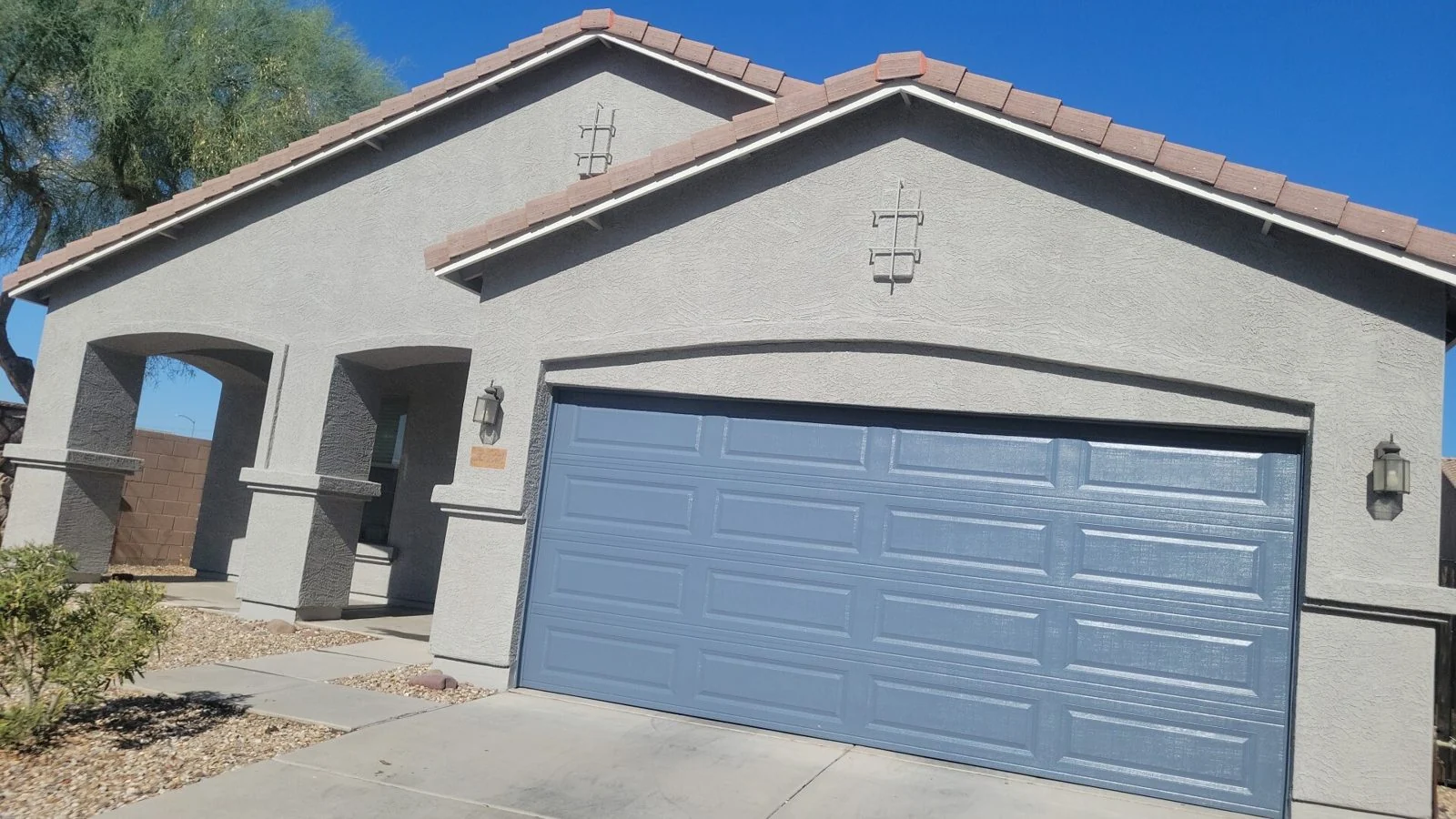 Freshly painted gray stucco home with a slate-blue garage door and tile roof in Peoria, Arizona